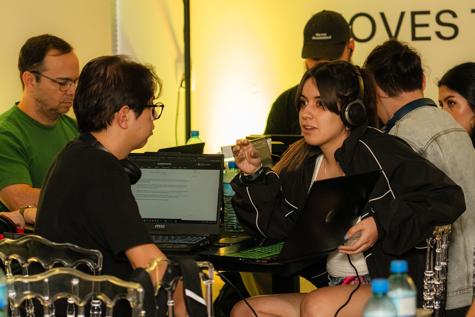 Builders with laptops and headphones around a hackathon table